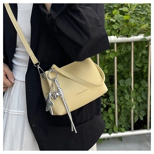 Détail du sac bandoulière jaune texture litchi avec pendentif étoile et pompon