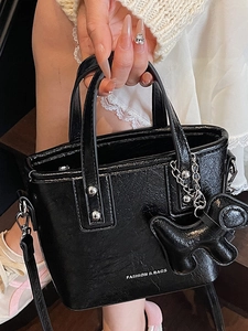 Glossy black patent leather bucket bag with silver studs and a decorative dog charm
