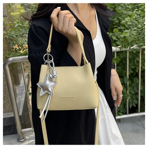 Détail du sac seau crème avec texture litchi et pendentif en forme d'étoile