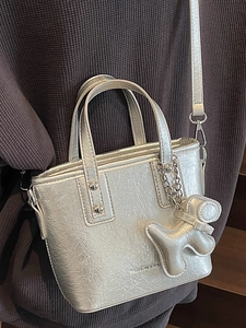 Silver metallic pleated bucket bag for women with a cute puppy charm and shoulder strap