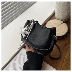 Détail du sac seau en cuir grainé noir avec breloque étoile argentée et texte mode