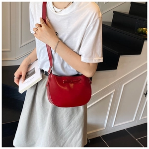 Détail du sac sous le bras en cuir bordeaux avec un nœud délicat et silhouette courbe