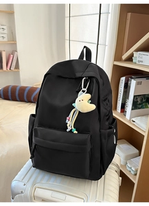 Details eines schwarzen Nylon-Rucksacks mit Mond-Anhänger auf einem weißen Koffer