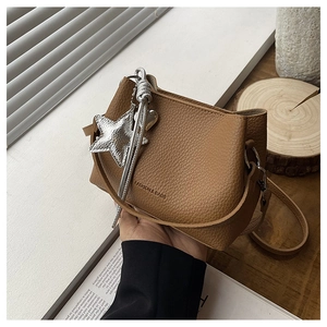 Détail d'un sac seau marron en cuir litchi avec pendentif étoile argenté élégant