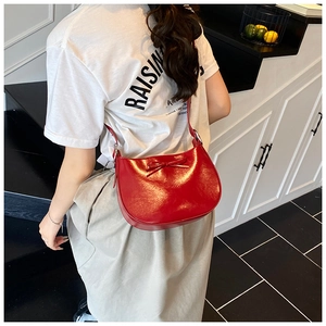 Gros plan d'un sac à bandoulière en cuir verni rouge avec détail de nœud sur un mannequin