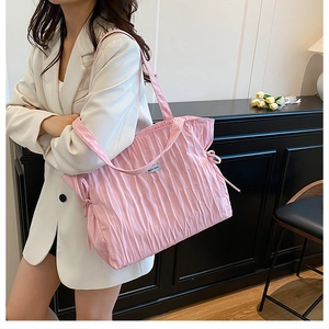 Détail d'un sac cabas plissé rose montrant le tissu texturé et le cordon de serrage latéral