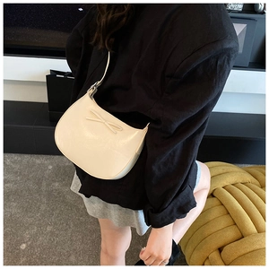 Détail du sac croissant blanc crème avec un élégant nœud décoratif et bandoulière réglable