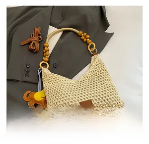 Detail of woven beach bag featuring yellow wooden beads, charms and cotton mesh texture