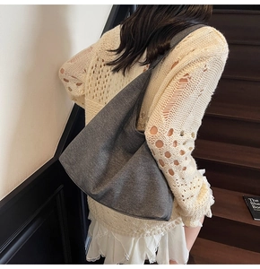 Close-up of dark grey fabric hobo bag worn by a model on a natural wooden staircase