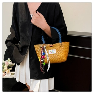 Close-up of handmade straw bag with blue denim handles and colorful fashion bag charms