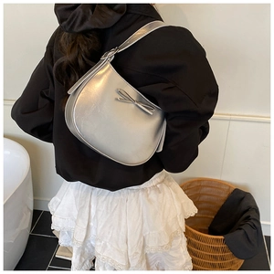 Détail du sac hobo argenté avec nœud porté par un mannequin, vue de dos montrant l'effet