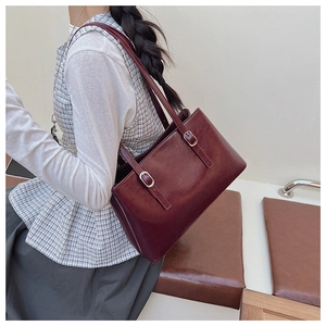 Detail of adjustable straps and metal buckles on a burgundy PU leather tote bag