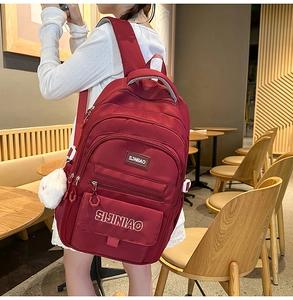 Detail van bordeauxrode waterdichte schooltas met meerdere ritslagen en pluche hanger