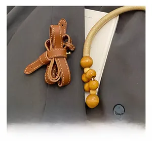 Detail of adjustable leather shoulder strap with white stitching and wooden bead accents