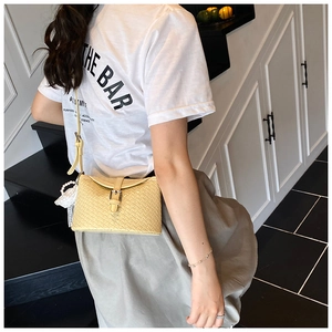 Détail du sac bandoulière en PU tressé jaune avec breloque perle et boucle en métal