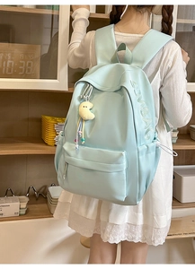 Detail eines hellblauen Rucksacks mit Buchstabenstickerei und süßem gelben Mondanhänger