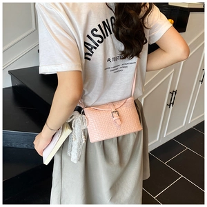 Détail du sac seau rose tressé avec ruban de perles en dentelle et boucle en métal