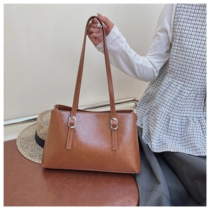 Detail view of brown PU leather tote bag with silver metal buckles and retro oil wax texture