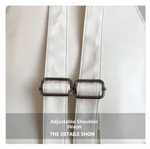 Detail of adjustable white leather shoulder straps with dark gunmetal buckles on a backpack