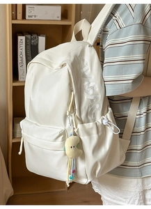 Detailansicht des cremefarbenen Rucksacks mit SIMBAG-Stickerei und Plüschmond-Anhänger