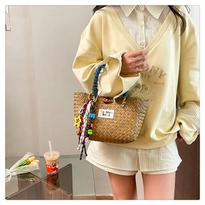 Detail of woven straw tote with denim handle and colorful fashion letter charms