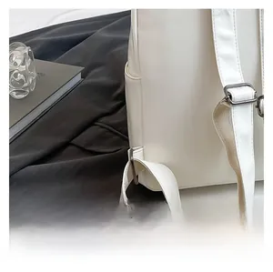 Detailed close-up of white leather backpack showing adjustable silver buckle and side pocket