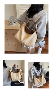 Detail of beige canvas tote bag with brown leather handles and side slogan print