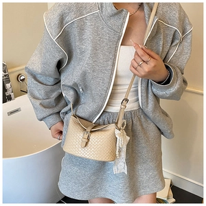 Détail du sac seau tissé beige avec breloques en perles et dentelle et bandoulière