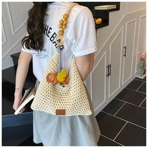 Detail of off-white woven beach bag with wooden bead strap and leather elephant charm