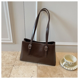 Detail view of a vintage dark brown shoulder bag with shiny finish and silver buckles