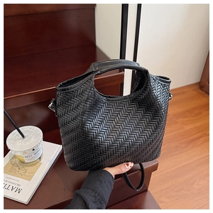 Detailed close-up of the black woven leather texture and metal strap rings on the bag