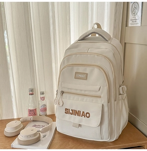 Gedetailleerde weergave van beige minimalistische rugzak met geborduurd logo en vakken