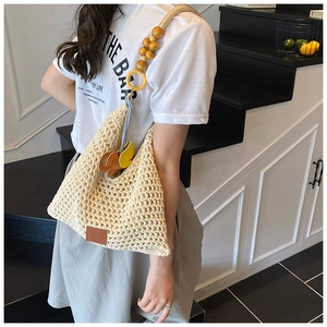 Detailed close-up of beige crochet tote bag with wooden bead straps and elephant charm