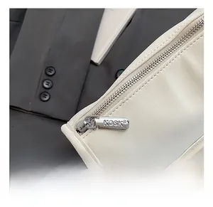 Close-up of polished silver zipper with KOSK engraving on a beige leather underarm bag
