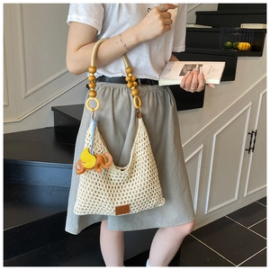 Detail view of beige crochet tote with wooden bead handle and orange elephant leather charm