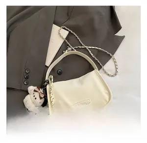 Close-up of stylish off-white crossbody bag with silver chain and cute bear charm