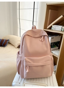 Minimalistischer rosa Rucksack auf weißem Koffer mit gepolsterten Trägern und Fächern