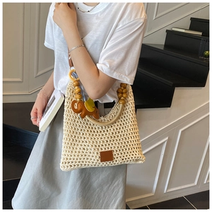 Detail of cream crochet beach bag with wooden bead handle and elephant charm