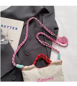 Dettaglio della borsa a secchiello in tela beige con ricamo kawaii rosa e corde intrecciate