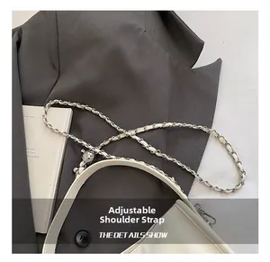 Close-up of a white leather bag with an adjustable chain strap on a grey suit jacket