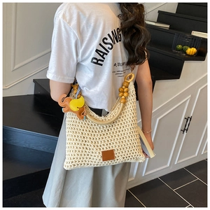 Detail of hand-woven beige beach tote with wooden beads and a cute elephant leather charm
