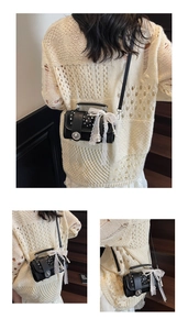 Detail of black mini crossbody bag with pearl studs and oversized white lace bow