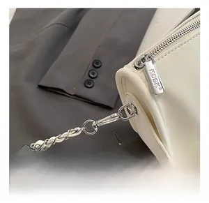 Detailed close-up of cream crossbody bag featuring silver chain strap and metal hardware