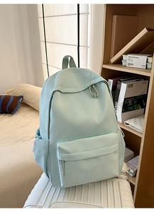 Detail eines mintgrünen Rucksacks mit großem Fassungsvermögen auf einem weißen Koffer