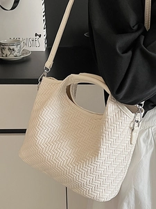 Elegant beige woven crossbody handbag with top handle and gold hardware in lifestyle setting