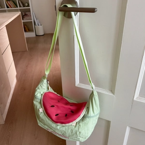 Detail of cute watermelon embroidery on light green fabric crescent bag hanging on door