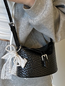 Sac seau tissé noir chic avec breloque en dentelle perlée porté par un mannequin stylé