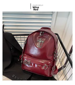 Detail view of wine red punk backpack featuring metal cross, rings, and glossy finish