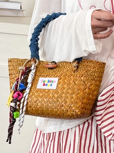 Handwoven straw tote bag with denim handles and decorative charms for summer beach vacation