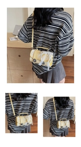Detail of yellow mini cylinder bag featuring pearl lace bow and silver twist lock